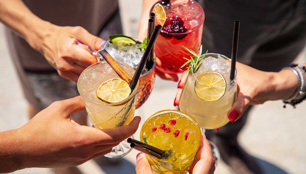 hands holding various cocktails
